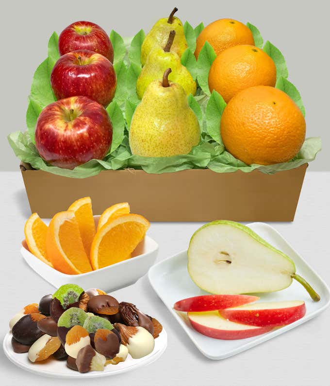 Gift box containing fresh apples, pears, and oranges, accompanied by a plate of assorted chocolate-dipped dried fruits and nuts, with sliced fruit displayed in the foreground.