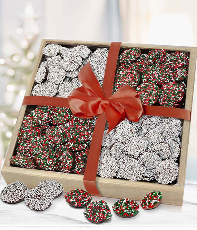  Box of festive chocolate candies covered in red, green, and white sprinkles, tied with a red ribbon bow, with a few candies scattered outside the box.