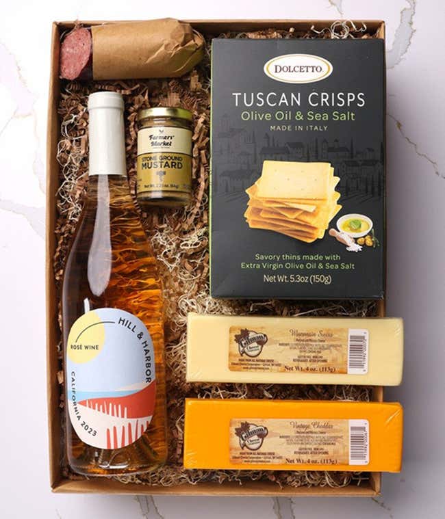A gift box with a bottle of California Ros&eacute; Wine, two types of cheese, crackers, stone-ground mustard, and a summer sausage.
