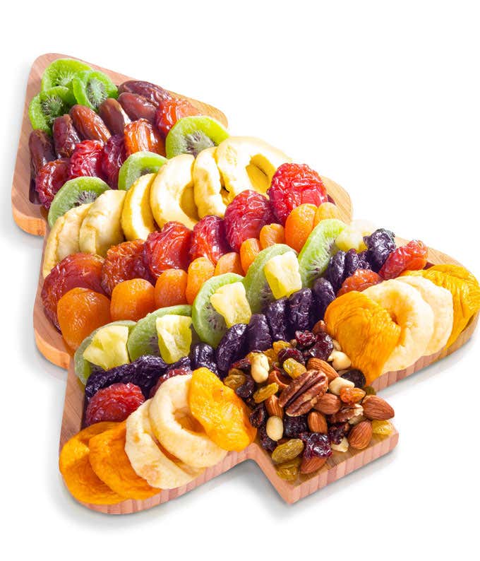 Christmas tree-shaped wooden tray filled with an assortment of dried fruits and nuts, including kiwi, pineapple, apples, apricots, dates, plums, and a mixed nut blend.