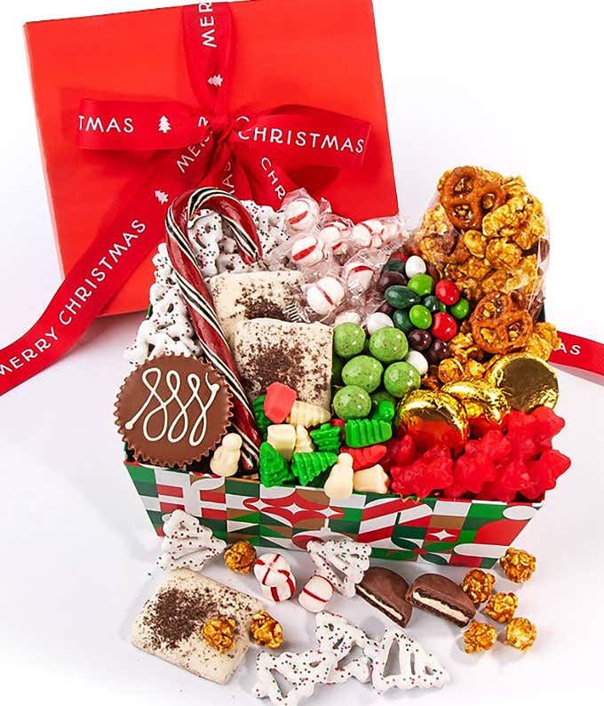 Festive Christmas gift box filled with a variety of holiday treats including caramel popcorn, chocolate-covered pretzels, peppermint candies, green and red candies, chocolate-covered cookies, and bark, all wrapped with a red Merry Christmas ribbon.