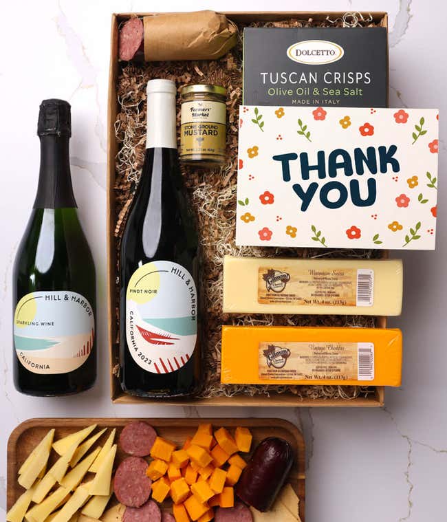 A gift box with two bottles of California wine (Pinot Noir and Sparkling Wine), two types of cheese, crackers, stone-ground mustard, a summer sausage, and a Thank You message card. 