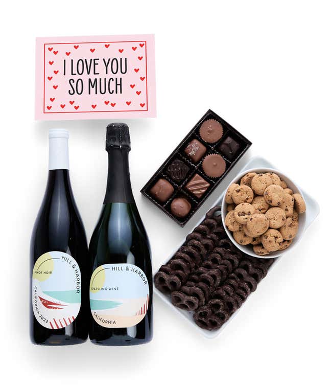 A gift box with chocolate pretzels, chocolate graham crackers, red velvet cookies, hazelnut wafer rolls, an 8 piece box of chocolates, 2 bottles of wine and an I Love You message card.